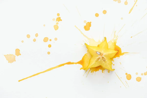 Elevated view of sweet star fruit on white surface with yellow paint splashes — Stock Photo