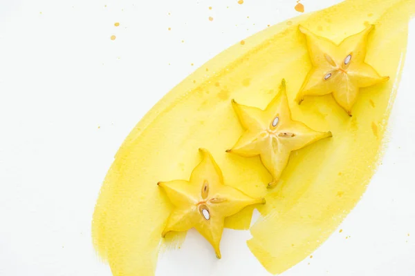 Top view of exotic sweet star fruits on white surface with yellow watercolor — Stock Photo