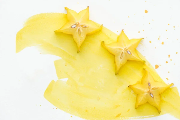 Підвищений вид смачних жовтих зіркових фруктів на білій поверхні з жовтим акварелем — стокове фото