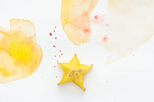 Vista superior de una carambola exótica sobre una superficie blanca con acuarela amarilla - foto de stock