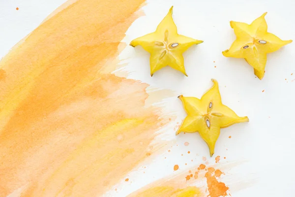 Vista dall'alto di frutti stellati su superficie bianca con acquerello arancione — Foto stock