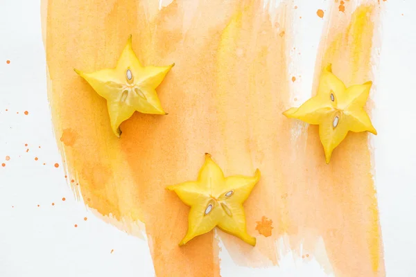 Vue de dessus de délicieux fruits étoilés sur la surface blanche avec aquarelle orange — Photo de stock