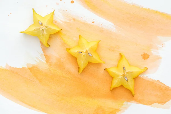 Top view of sweet exotic star fruits on white surface with orange watercolor — Stock Photo