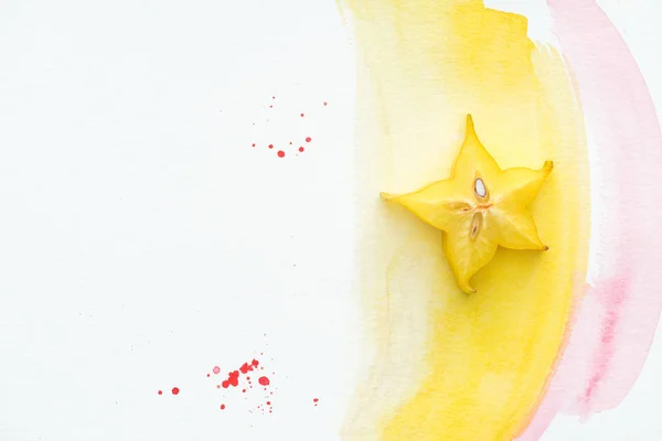 Top view of carambola on white surface with yellow and pink watercolors — Stock Photo