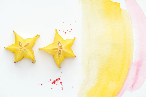 Vista superior de dois frutos de estrela exóticos na superfície branca com aquarela amarela e rosa — Fotografia de Stock
