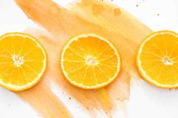 Вид зверху на три помаранчеві шматочки на білій поверхні з помаранчевим акварелем — стокове фото