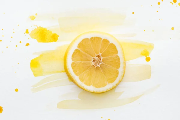 Elevated view of lemon piece on white surface with yellow watercolor — Stock Photo