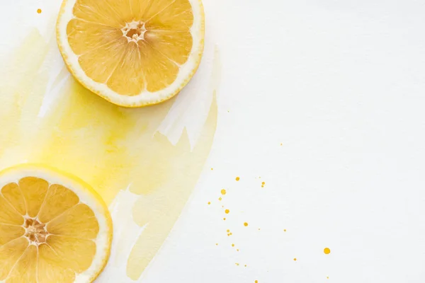 Vue de dessus des morceaux de citron délicieux sur la surface blanche avec aquarelle jaune — Photo de stock