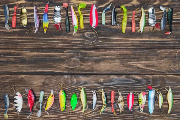 Vue d'en haut de divers appâts de pêche placés en rangées sur un fond en bois — Photo de stock