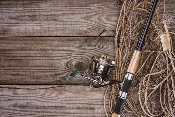 Vue de dessus du filet de pêche et de la canne à pêche sur des planches en bois — Photo de stock