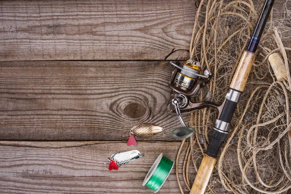 Vista superior do carretel, haste de pesca, isca e rede de pesca no fundo de madeira — Fotografia de Stock