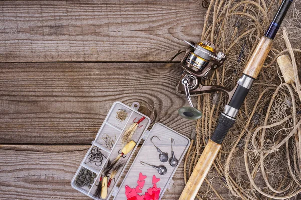 Flat lay com rede de pesca, haste de pesca e caixa de plástico com equipamento de pesca e ganchos em tábuas de madeira — Fotografia de Stock