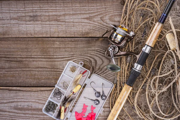 Tendido plano con red de pesca, caña de pescar y caja de plástico con aparejos de pesca y ganchos en tablones de madera - foto de stock