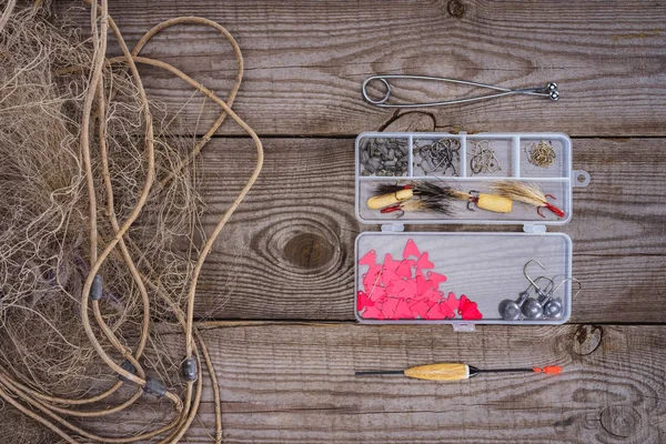 Vista sopraelevata di rete da pesca e scatola di plastica con attrezzatura da pesca e ganci su fondo di legno — Foto stock