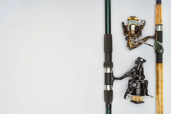 Vista superior de dos cañas de pescar dispuestas aisladas sobre un concepto blanco y minimalista - foto de stock
