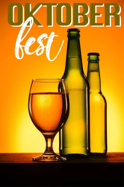 Bottles and glass of beer on surface on orange background with 