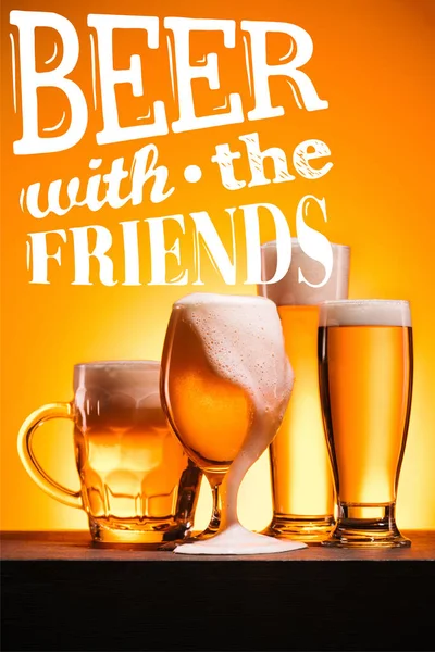 Mugs of cold beer with froth on orange background with 