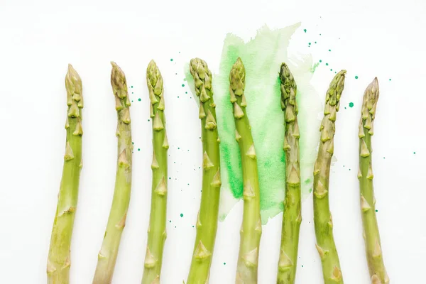 Vue du haut de la rangée d'asperges mûres sur une surface blanche avec des traits d'aquarelle verts — Photo de stock