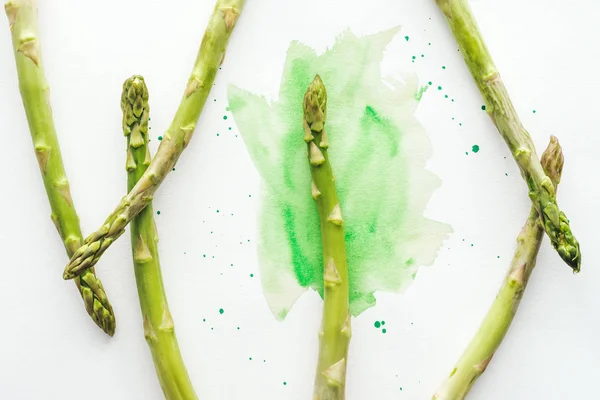 Vue de dessus des tiges d'asperges sur la surface blanche avec des traits d'aquarelle verts — Photo de stock