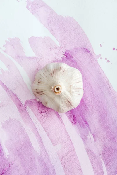 Top view of whole raw garlic on white surface with pink watercolor strokes — Stock Photo