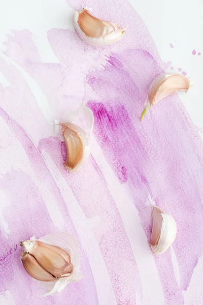 Vista superior de delicioso alho cru na superfície branca com traços de aquarela rosa — Fotografia de Stock