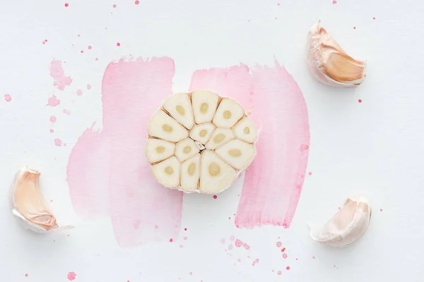 Top view of spiced spicy garlic on white surface with pink watercolor strokes — Stock Photo