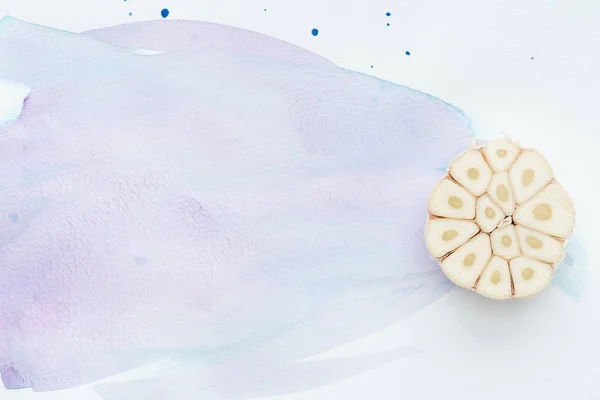 Vista superior de ajo crudo picante en la superficie blanca con trazos de acuarela púrpura - foto de stock