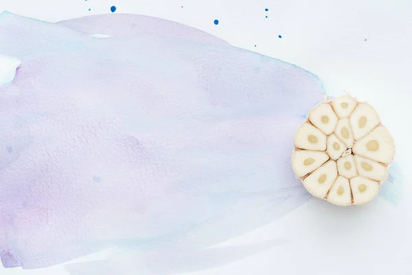 Top view of spicy raw garlic on white surface with purple watercolor strokes — Stock Photo