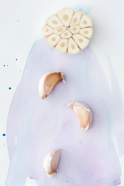 Top view of spicy garlic on white surface with purple watercolor strokes — Stock Photo