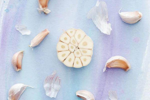 Vista dall'alto di aglio affettato maturo sulla superficie bianca con tratti di acquerello viola — Foto stock