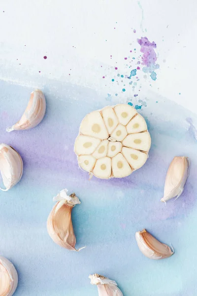 Draufsicht auf geschnittenen Knoblauch auf weißer Oberfläche mit violetten Aquarellstrichen — Stockfoto