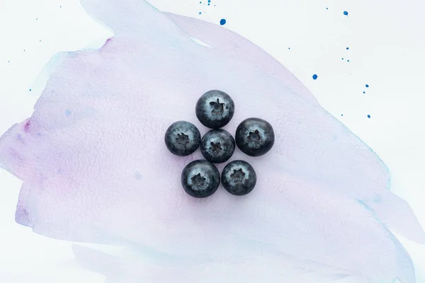 Top view of ripe blueberries on white surface with purple watercolor strokes — Stock Photo