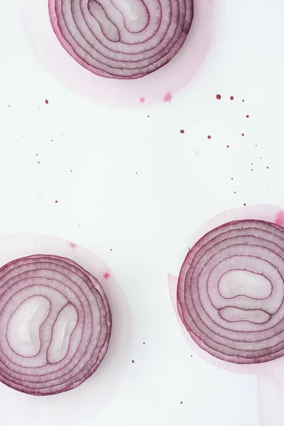 Draufsicht auf aufgeschnittene rote Zwiebel auf weißer Oberfläche mit rosa Aquarellflecken — Stockfoto