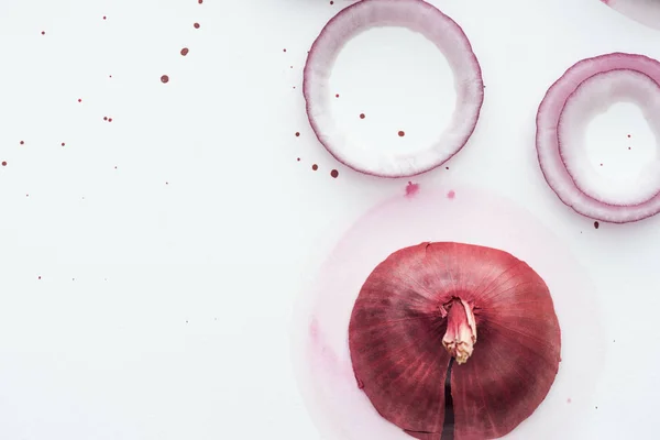 Vista superior de cebola vermelha inteira com anéis na superfície branca com manchas de aquarela rosa — Fotografia de Stock