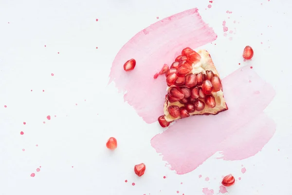 Top view of pomegranate on white surface with pink watercolor strokes — Stock Photo