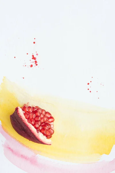 Vista superior de romã deliciosa na superfície branca com traços de aguarela amarelos e rosa — Fotografia de Stock
