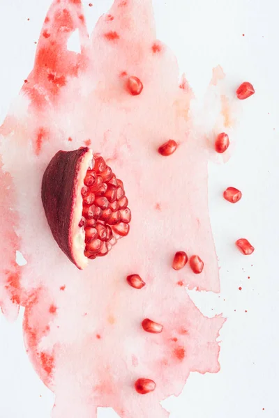 Top view of tasty pomegranate on white surface with red watercolor strokes — Stock Photo