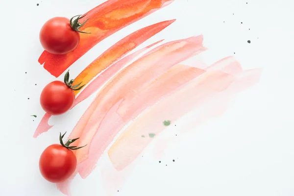 Top view of row of cherry tomatoes on white surface with red watercolor strokes — Stock Photo