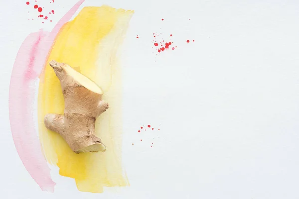 Top view of half of ginger root on white surface with yellow watercolor strokes — Stock Photo