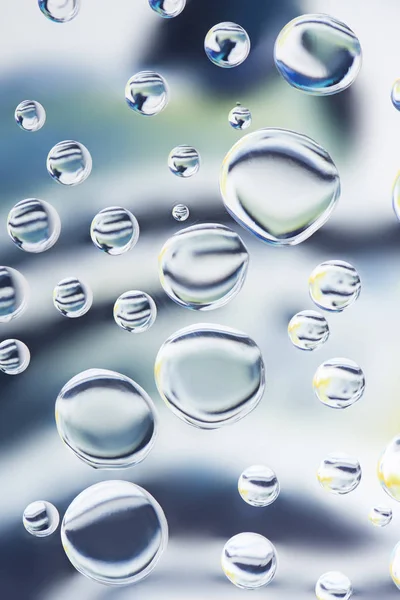 Vue rapprochée de belles gouttes d'eau transparentes sur fond flou clair — Photo de stock