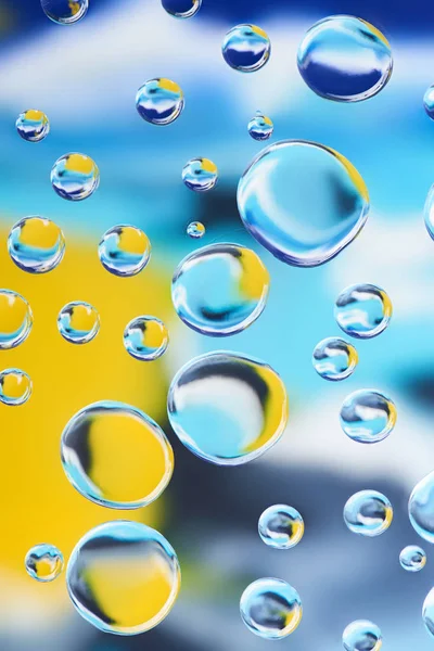 Vista de cerca de hermosas gotas de agua limpia sobre fondo abstracto colorido borroso - foto de stock