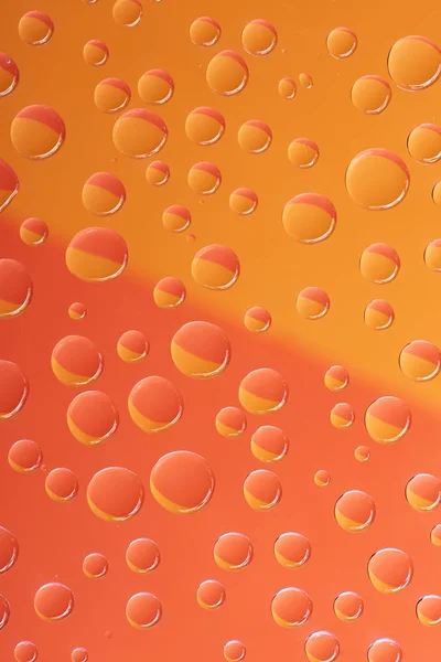 Vista de cerca de gotas de agua transparentes sobre fondo naranja brillante - foto de stock