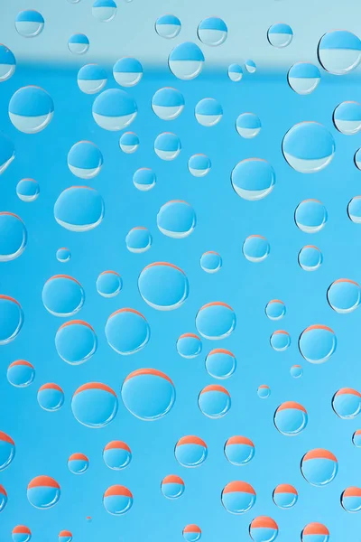 Крупный план прозрачных капель воды на ярко-голубом фоне — стоковое фото