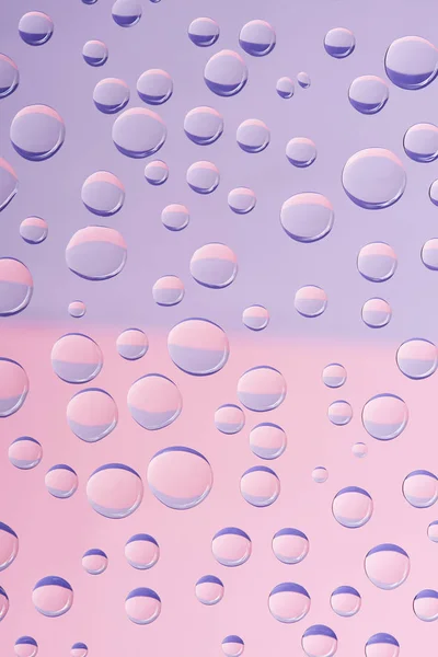 Vista de cerca de gotas de agua transparentes sobre fondo rosa claro - foto de stock