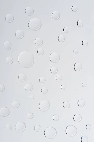 Vista de cerca de gotas de agua transparentes sobre fondo gris claro - foto de stock