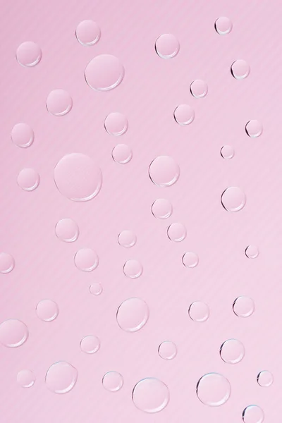 Vista close-up de gotas de água transparentes no fundo rosa — Fotografia de Stock