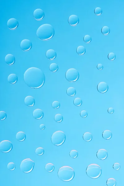 Vue rapprochée de gouttes d'eau transparentes sur fond bleu — Photo de stock