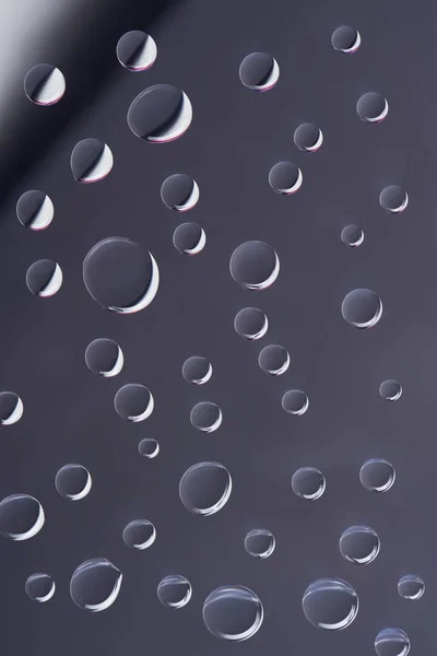 Close-up view of transparent calm droplets on grey background — Stock Photo