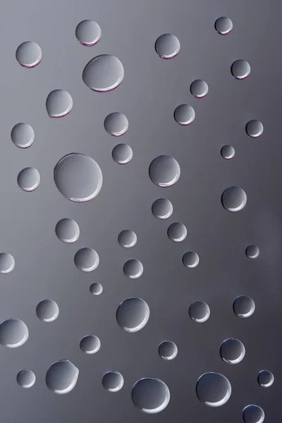 Close-up view of transparent clear droplets on grey background — Stock Photo