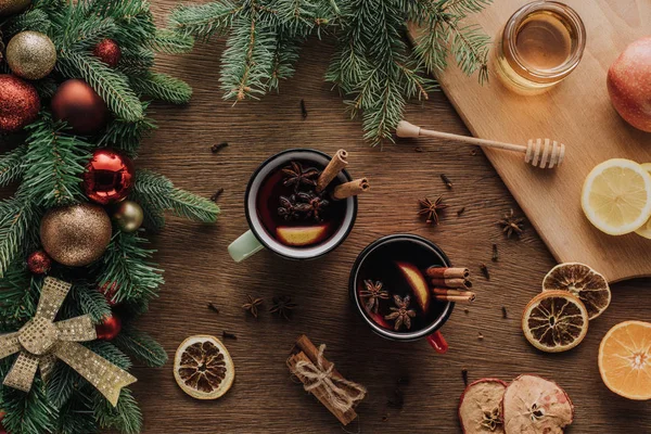 Vue du dessus des tasses de vin chaud et de brindilles de sapin avec des boules sur table en bois, concept de Noël — Photo de stock